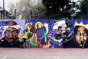 A tagging of Tupac and Notorious B.I.G. on a cement wall in bright colors and exquisite depiction.