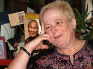 Eve Sedgwick sitting positioned with her head resting on her hand, smiling slightly.